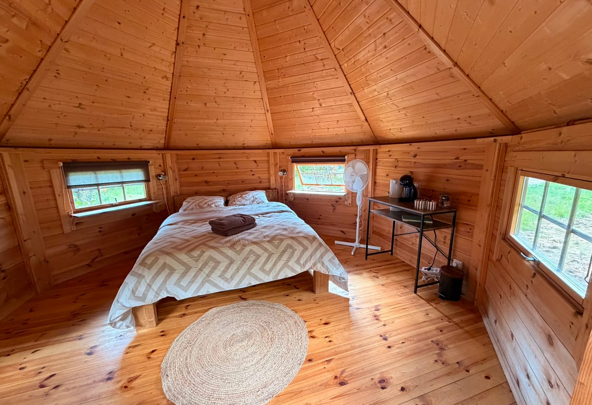 Intérieur d'un chalet des Cabanes de Condé — bois clair, lit double sous charpente en pointe