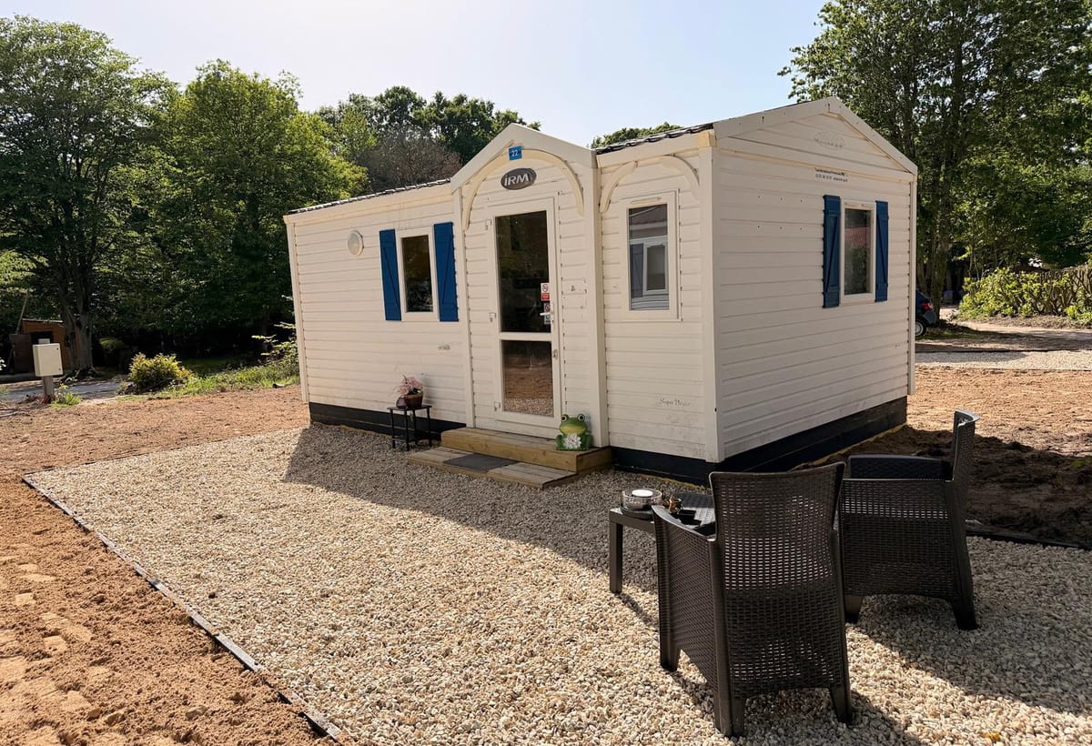 Mobil-home des Cabanes de Condé avec volets bleus et terrasse en gravier